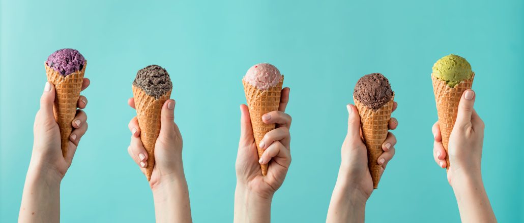 Hands holding ice cream in cones on blue background